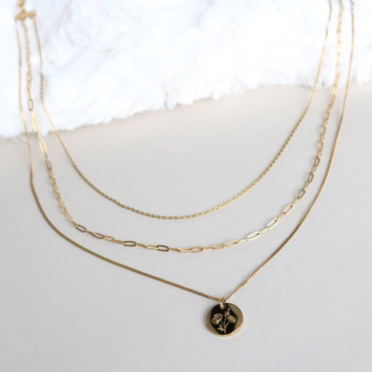 Two gold necklaces on a white surface