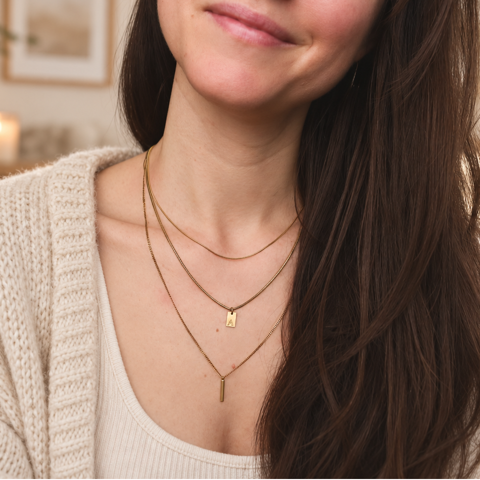 Woman's neckline wearing two layered gold chains with a green stone pendant