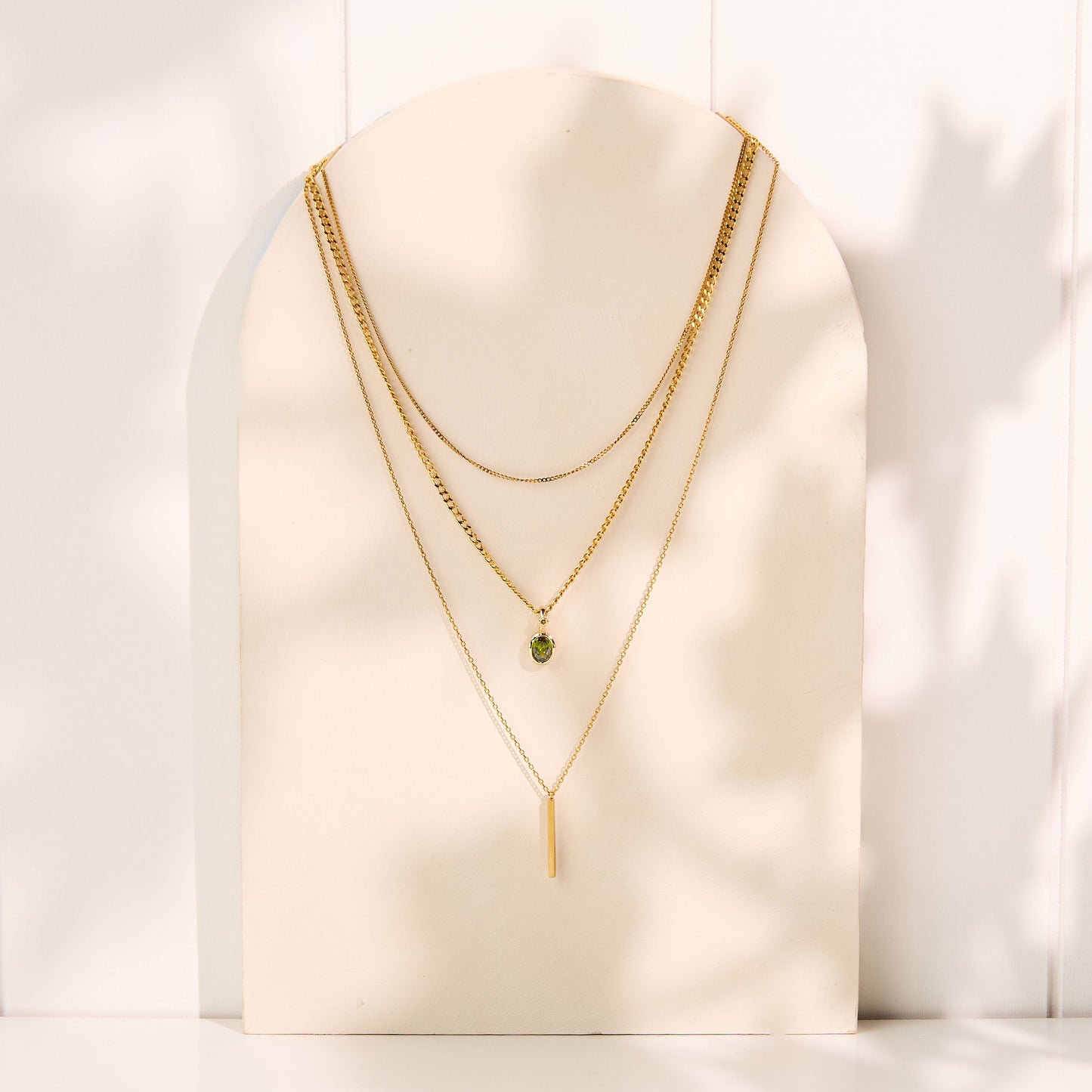 Gold necklaces on a white mannequin bust with a white background