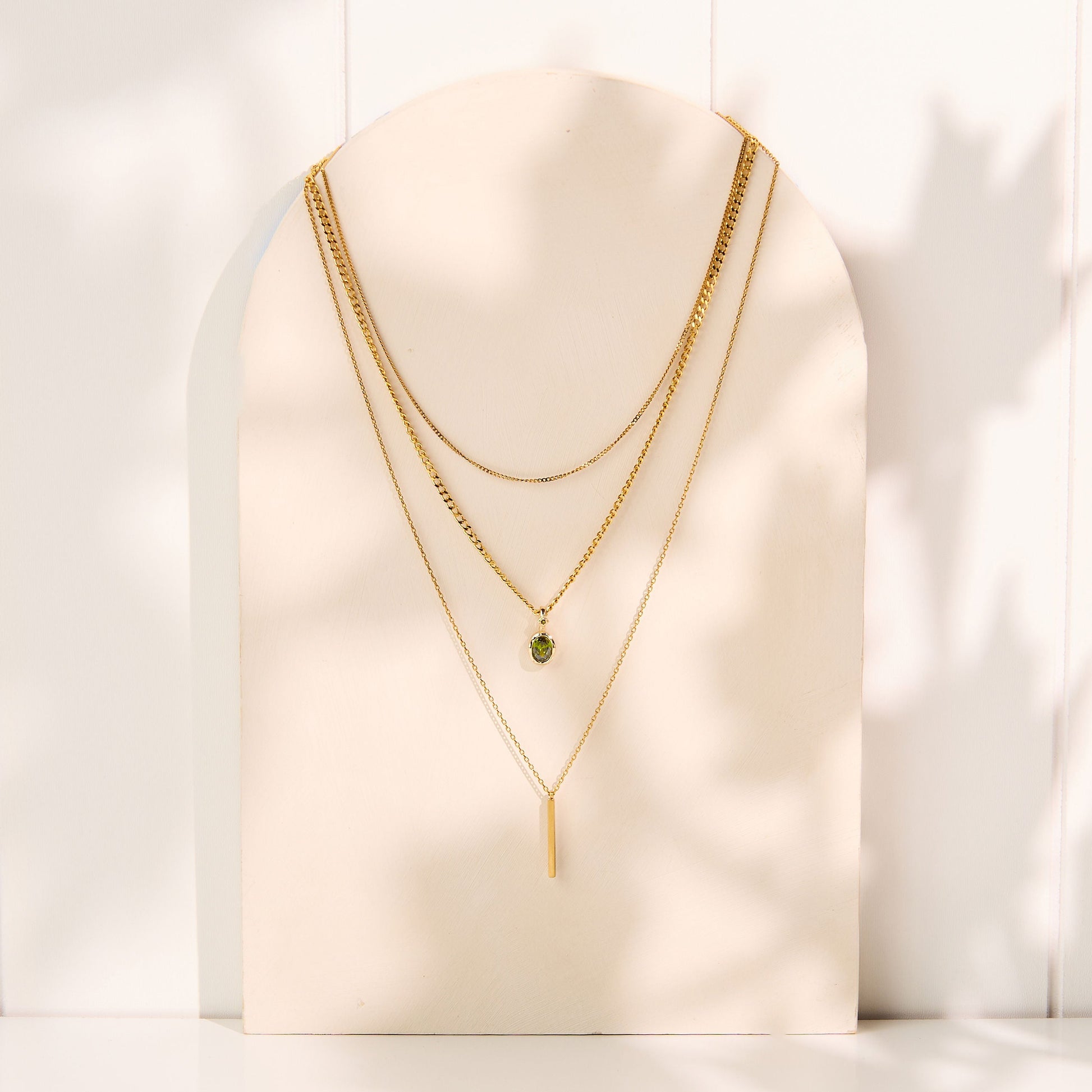 Gold necklaces on a white mannequin bust with a white background