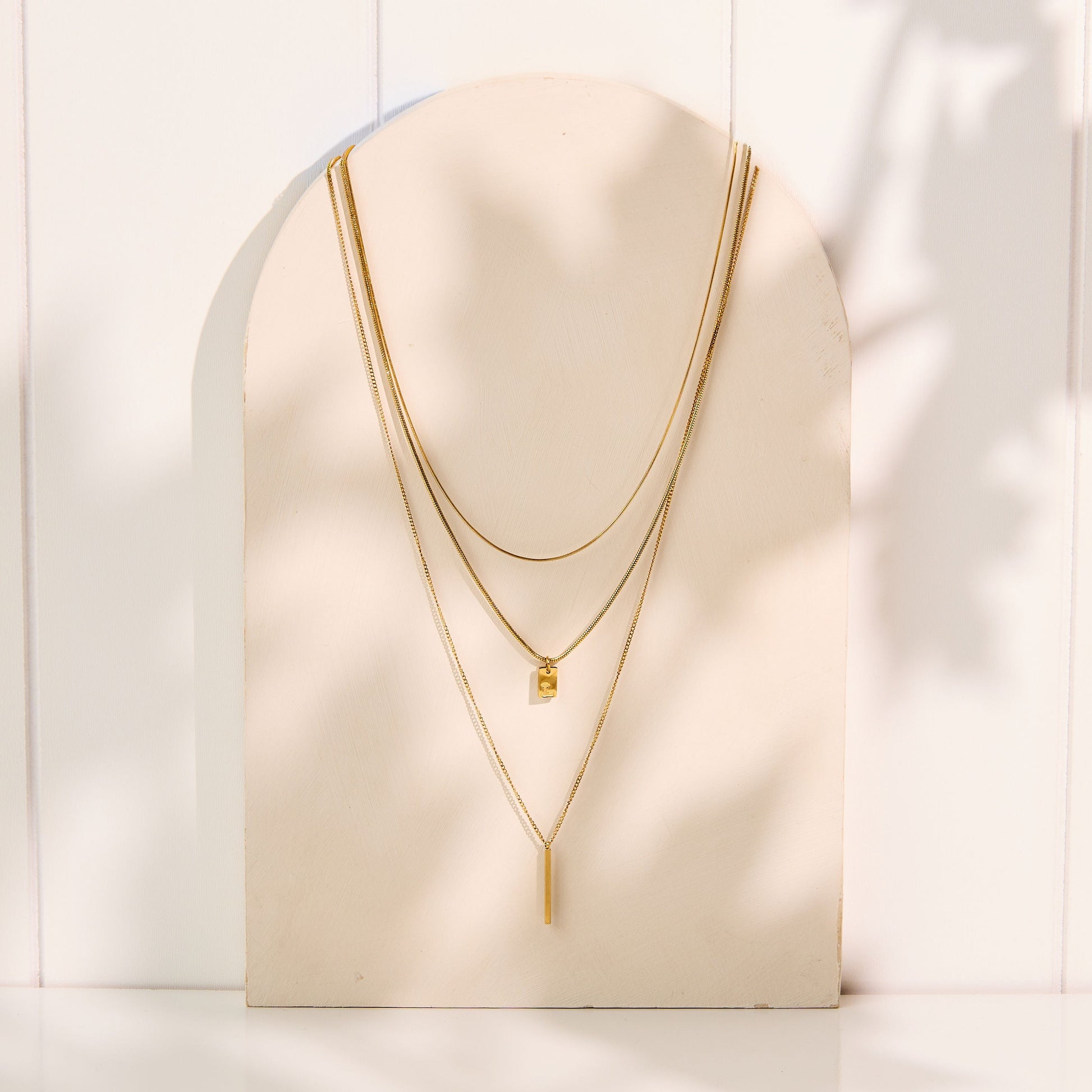 Gold necklace displayed on a mannequin bust against a white background