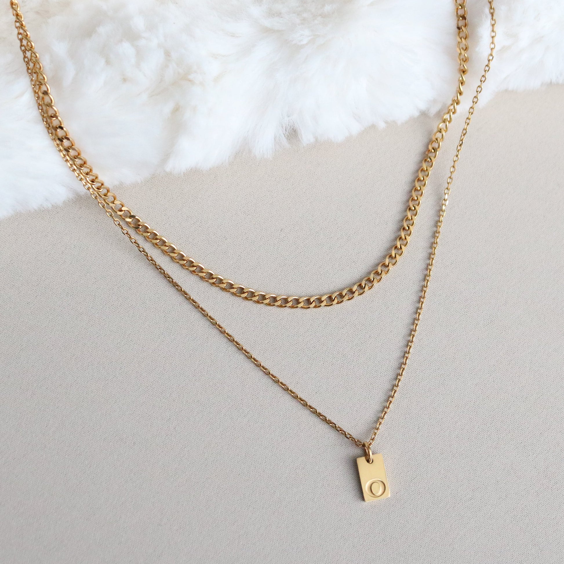 Gold chain necklace with a small pendant on a light surface