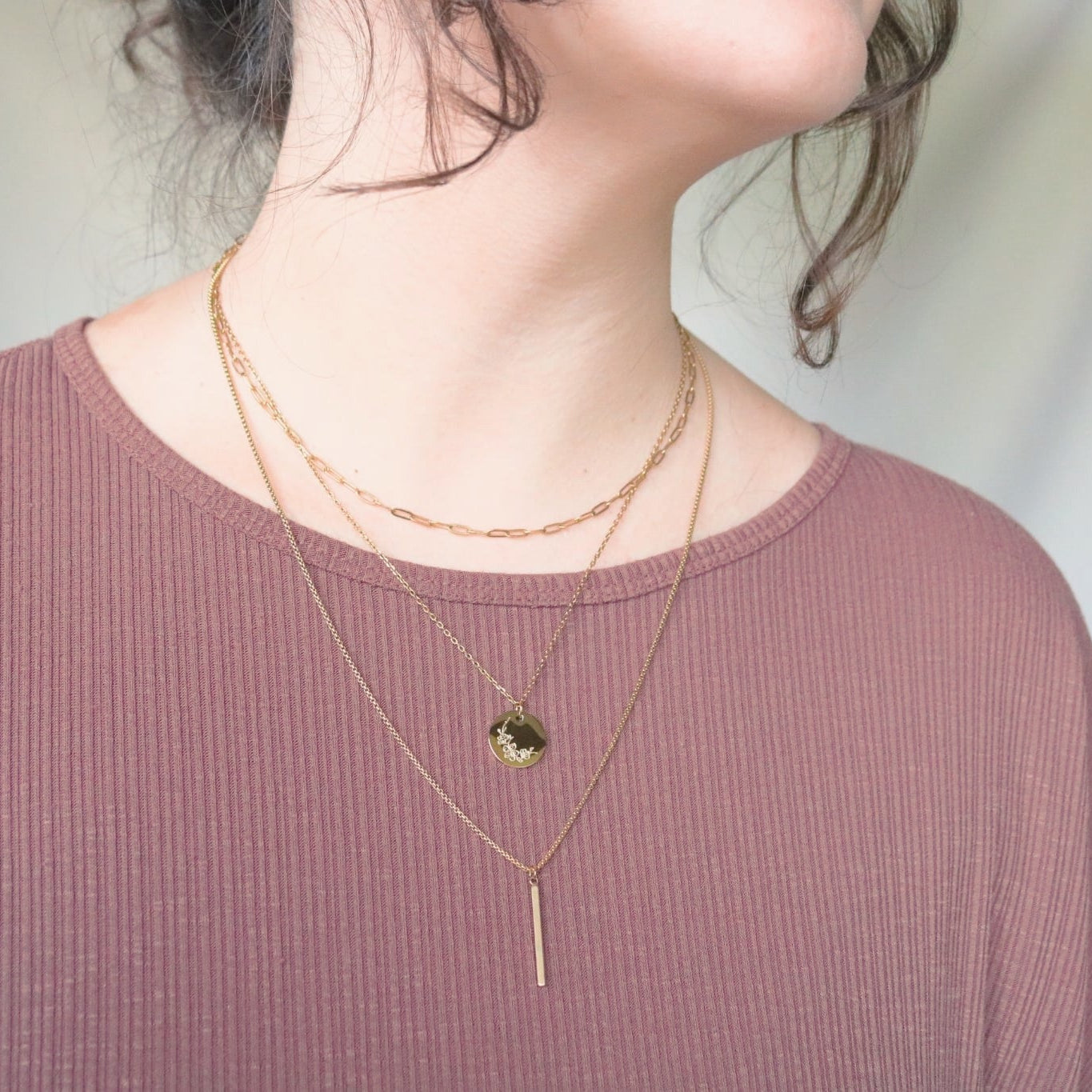 Person wearing a pink top with layered gold necklaces