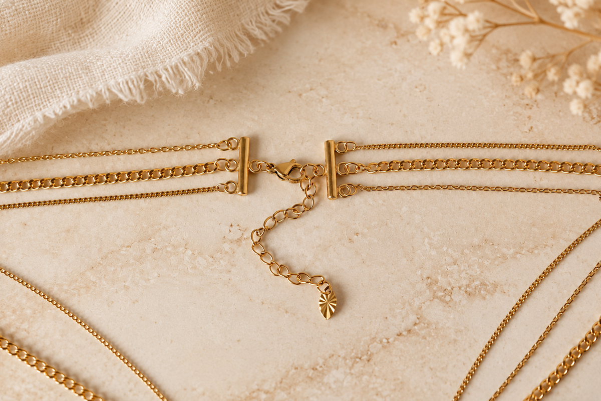 Close-up of a layered gold necklace clasp joining three chains with one lobster clasp