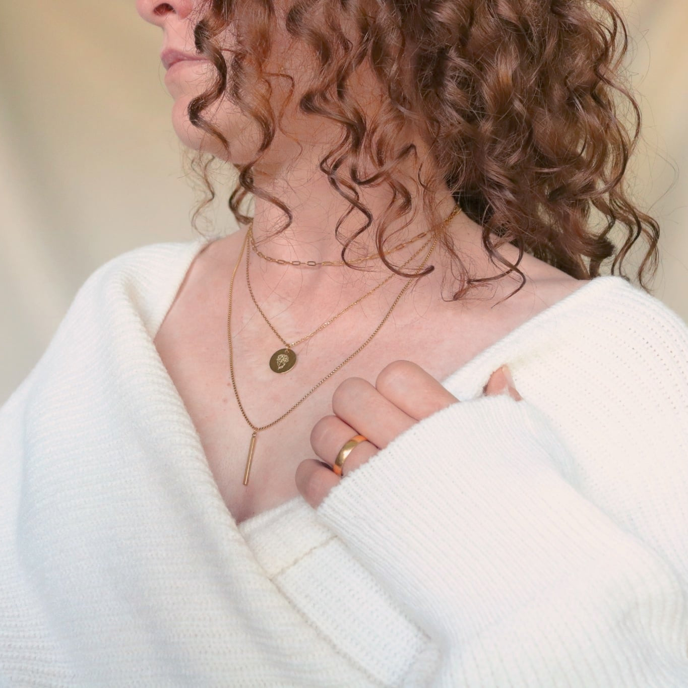 Person wearing a gold January birth flower necklace.
