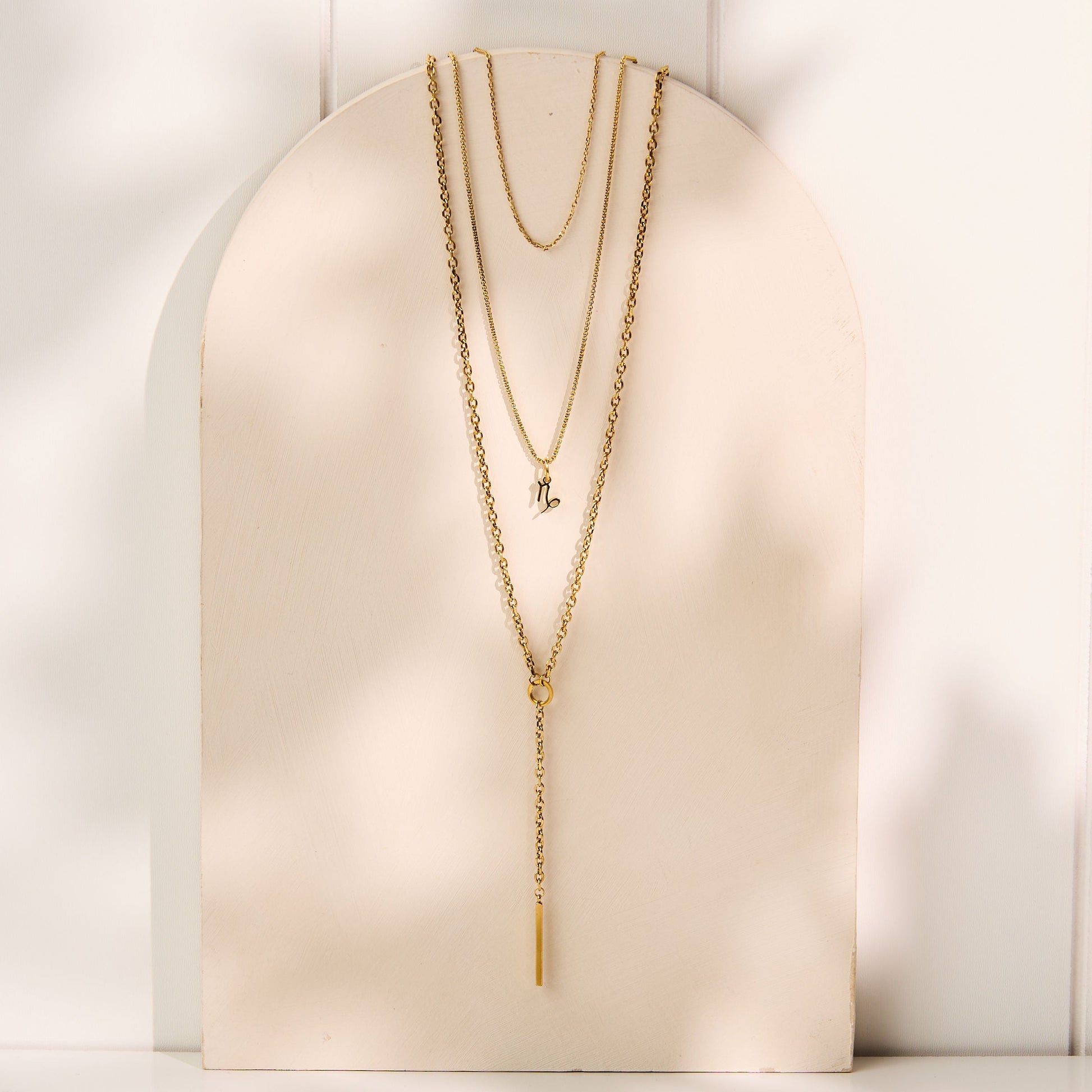 Gold Zodiac necklace on a white stand with a white background