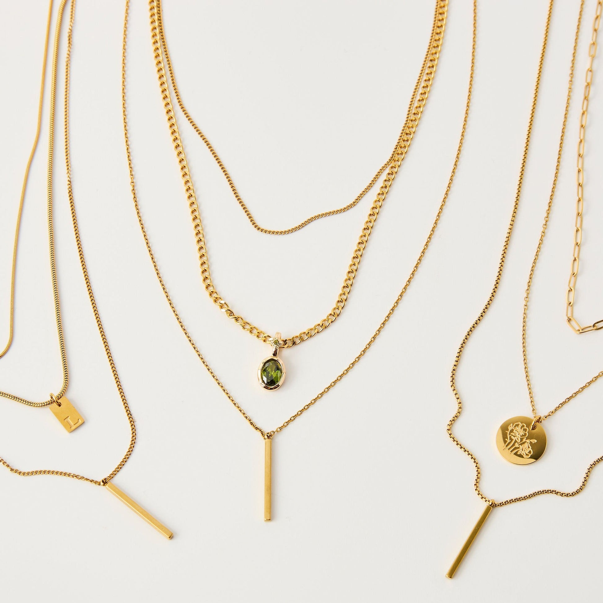 Set of gold necklaces with various pendants on a light background