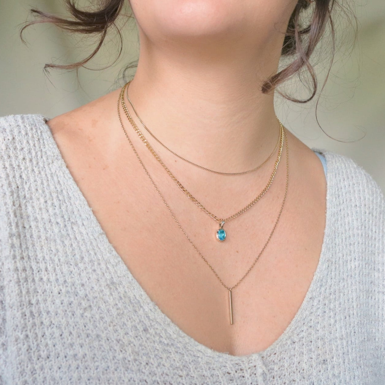 Necklace with a blue March Birthstone pendant worn by a person against a neutral background.