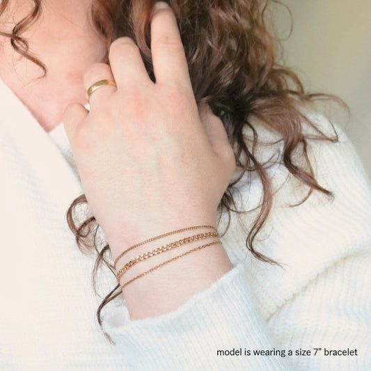 Person wearing gold bracelets on a blurred background